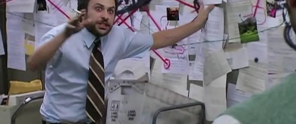A man pointing at a board of evidence in a conspiratorial way